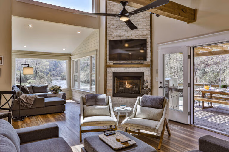 Cozy living space at The Farmhouse at Elestay with fireplace, high ceilings, and scenic North Georgia river views.