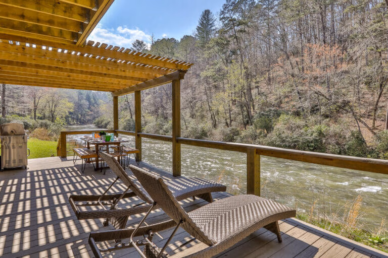 Pergola-covered outdoor seating and dining space at The Farmhouse at Elestay, Ellijay riverfront rental.